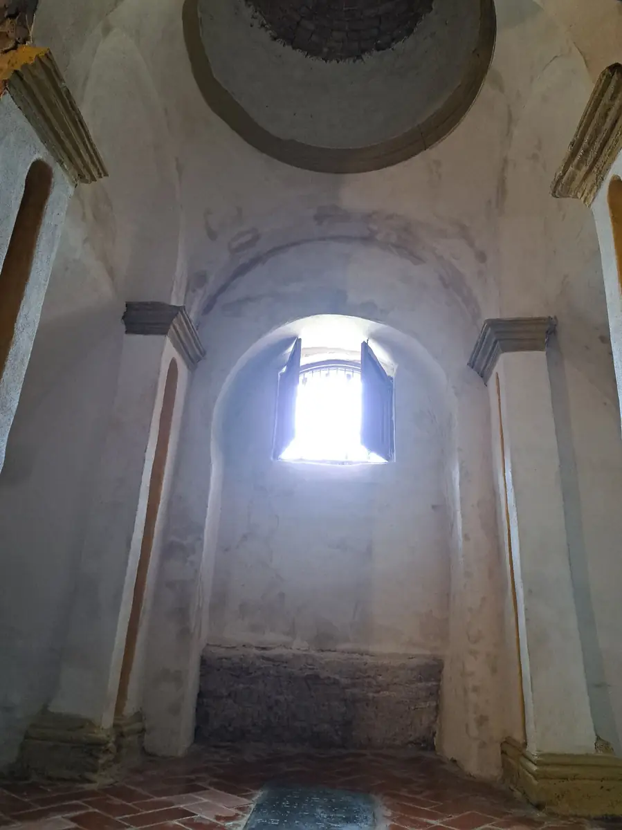 Interior de una cripta abovedada con una ventana en lo alto